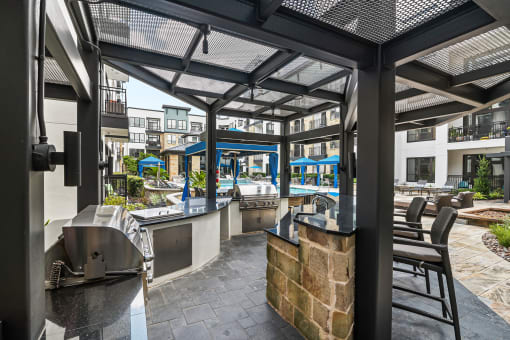 a patio with a bar and tables and a pool