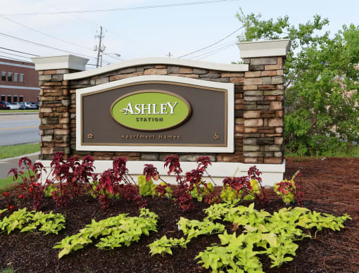 a sign in front of plants and flowers