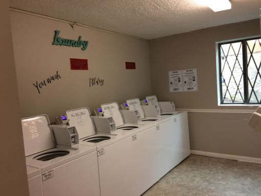 a laundry room with four washers and four dryers