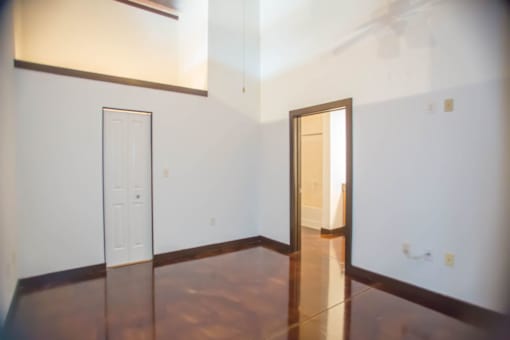 A room with a white door and a brown floor.