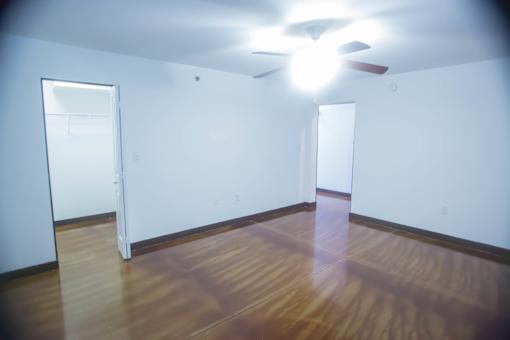 A room with a ceiling fan and wooden floors.