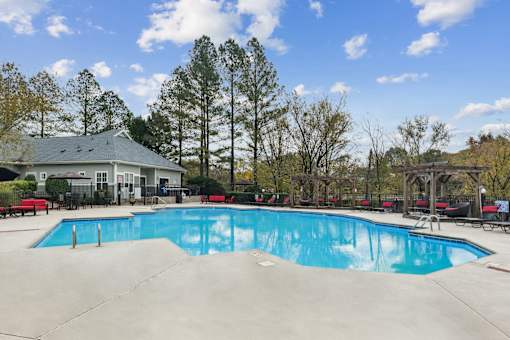A large swimming pool with a house and trees in the background.
