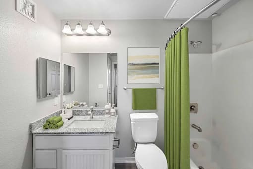 A bathroom with a green shower curtain and a white toilet.
