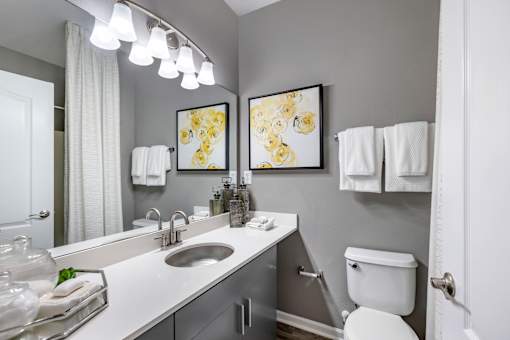 A bathroom with a white toilet, sink, and mirror.