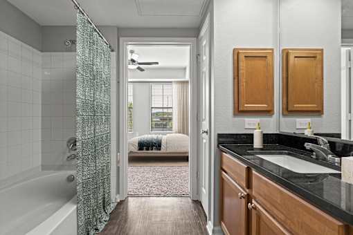 A bathroom with a black counter top and a white sink.