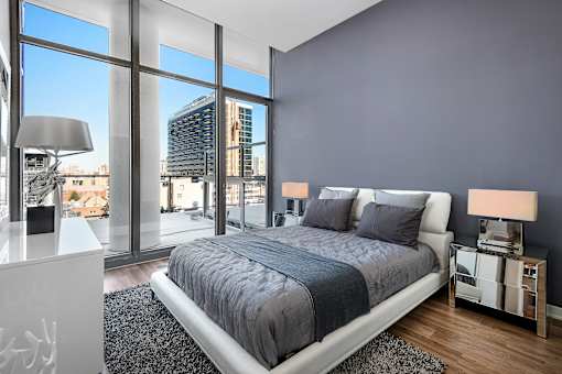A bedroom with a large bed and a view of the city outside the window.