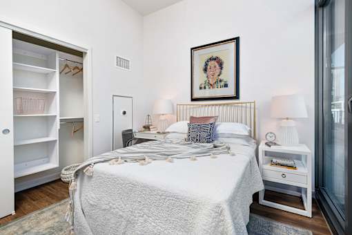A bedroom with a bed, nightstand, and a painting on the wall.