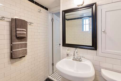 A white sink in a bathroom with a mirror above it.