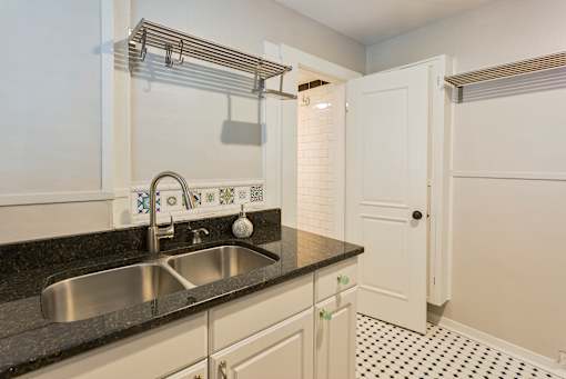 A kitchen with a sink and a black counter top.