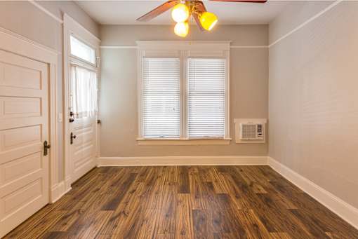 A room with a ceiling fan and wooden flooring.