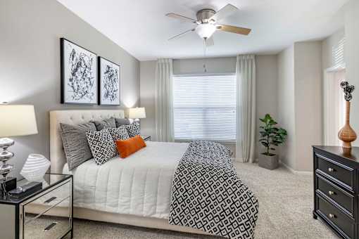 A bedroom with a bed, nightstand, and a ceiling fan.