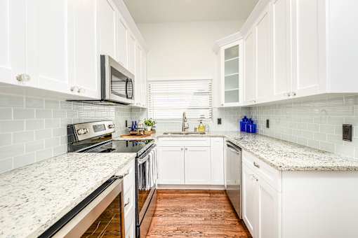 A kitchen with white cabinets and a granite countertop.