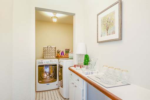 A kitchen with a white oven and microwave, a white countertop with a plant, and a framed picture on the wall.