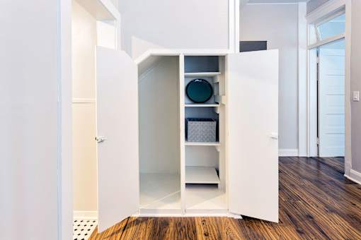A white kitchen cabinet with a glass door and shelves.