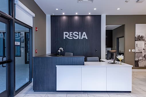 A reception area with a white counter and a sign that says "RESIA".