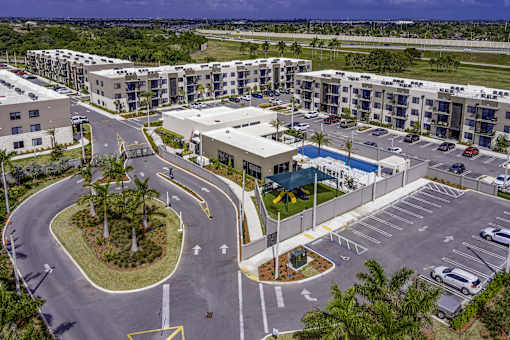 A parking lot with a roundabout and apartment buildings in the background.