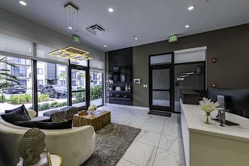 A modern waiting room with a sofa, coffee table, and a reception desk.