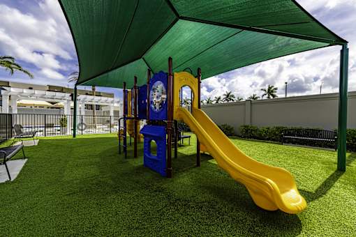 A playground with a yellow slide and a green canopy.