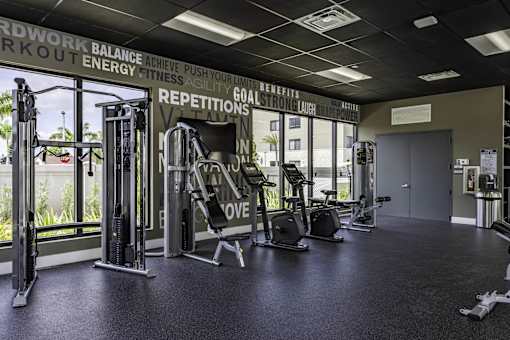 A gym with a variety of equipment including a squat rack, a leg press machine, and a treadmill.