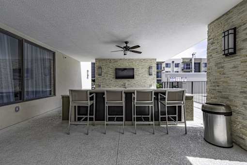 A patio with a table, chairs, and a TV mounted on a brick wall.