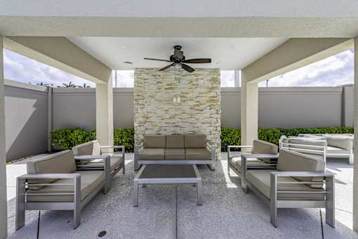 A patio with a table, chairs, and a fan.