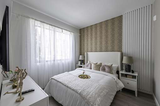 A bedroom with a large bed, a nightstand, and a window with curtains.