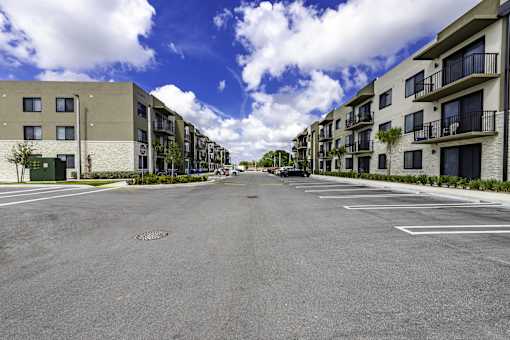 A street view of a residential area with apartment buildings on both sides and a car driving down the road.