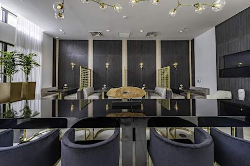 A black and gold dining room with a long table and chairs.