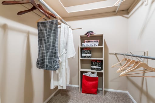 a walk in closet with a rack of clothes and a red bag on the floor