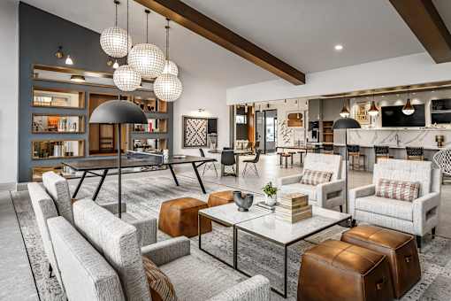 A modern living room with a grey sofa, a glass coffee table, and a large area rug.