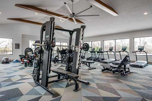 A gym with a variety of equipment including treadmills, weights, and a ceiling fan.