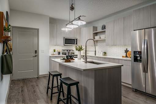 A kitchen with a white countertop and a stainless steel refrigerator.