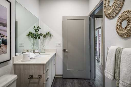 A bathroom with a sink, mirror, and towel rack.
