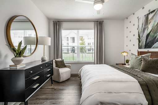 A bedroom with a large bed, a dresser, and a chair.