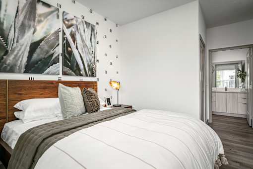 A bedroom with a large bed and a painting of a plant on the wall.