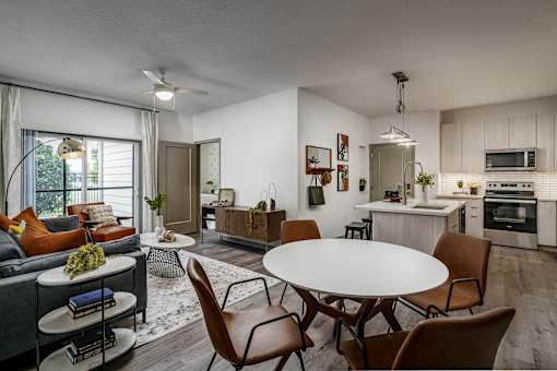 A modern living room with a grey couch, a white coffee table, and a dining table with chairs.