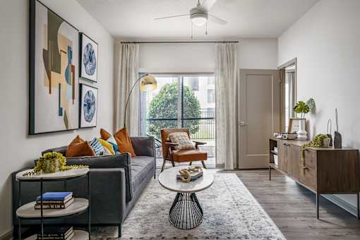 A living room with a grey couch, a coffee table, and a painting on the wall.