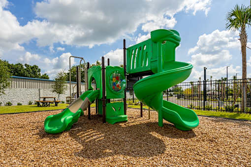 A green playground slide with a slide ladder.