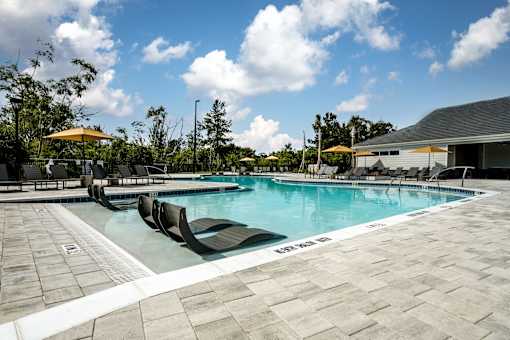 A large outdoor swimming pool surrounded by lounge chairs and umbrellas.