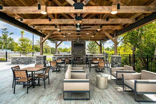 A wooden deck with chairs and tables is surrounded by a black fence.