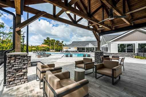 A wooden patio with a stone pillar and chairs.