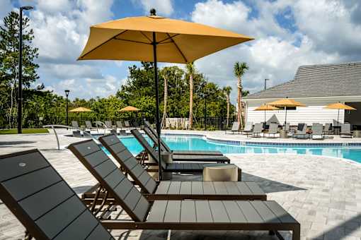 A sunny day at the pool with lounge chairs and umbrellas.