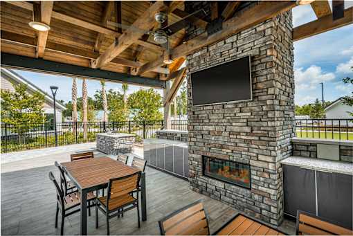A patio with a stone fireplace and a TV mounted on the wall.