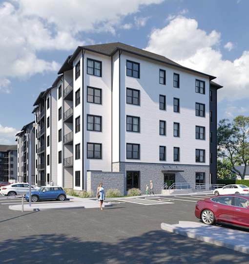 A modern apartment building with a parking lot in front.