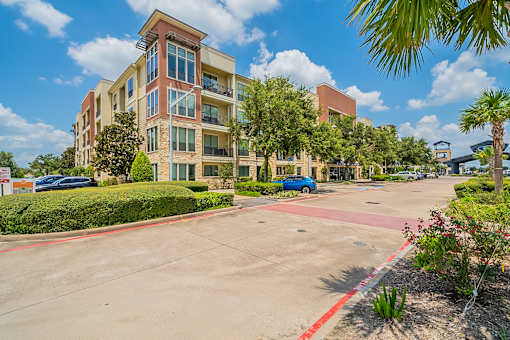 A multi-story apartment building with a parking lot in front.