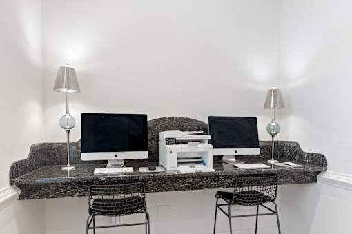 Two computers on a desk with two lamps on either side.
