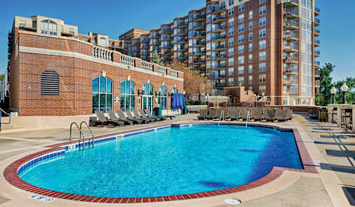A large swimming pool with a red brick building in the background.
