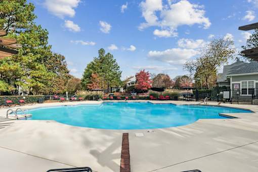 A large swimming pool surrounded by trees and a fence.