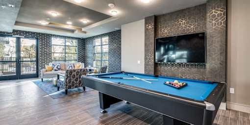 A pool table in a room with a television mounted on the wall.