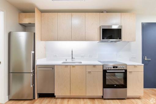 A kitchen with a refrigerator, microwave, and oven.